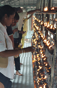 Ludzie zapalający świeczki w świątyni Buddhy w Kandy, gdzie znajduje się święta relikwia- ząb Buddhy